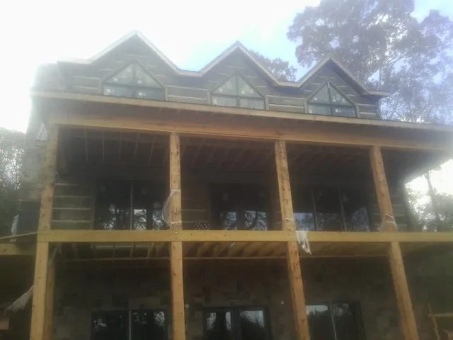 Dormers and porch framing on a large log home under construction — Roof Coating work by our crew in Sodus