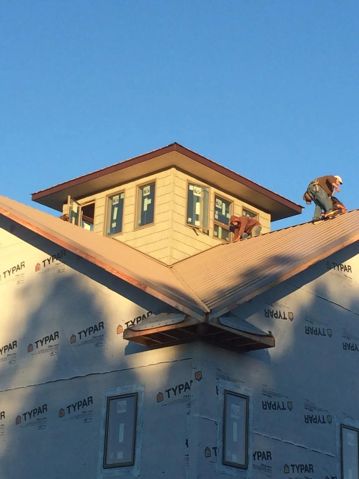Roofers working around a rooftop cupola on a new metal roof at sunset — Roof Waterproofing in Sodus by Roofing Brothers